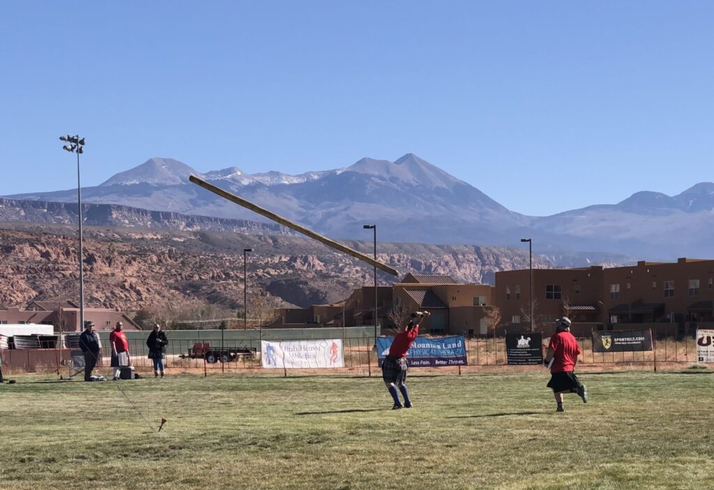 A man throws a caber (large pole) at the Highland Games